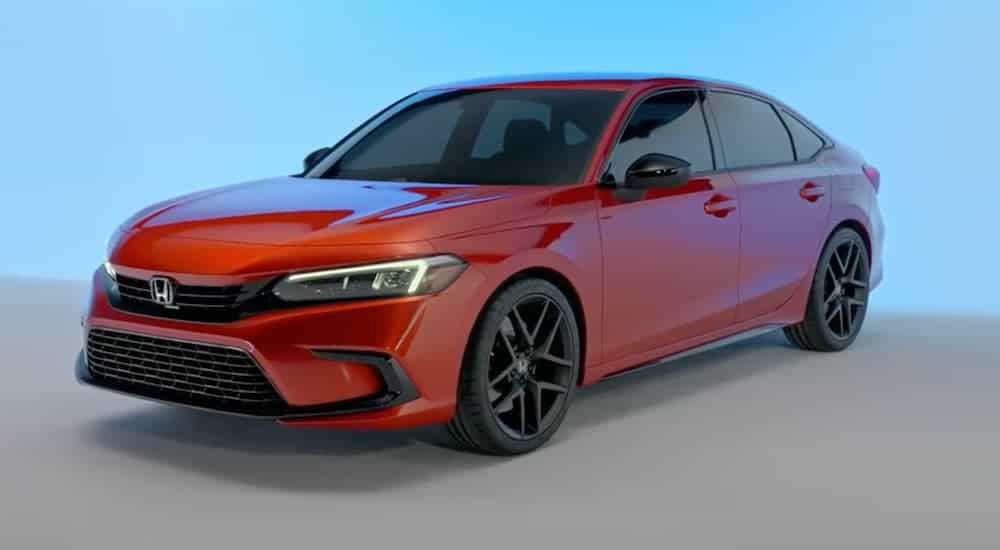 A red 2022 Honda Civic prototype is parked on a gray and blue background, soon to be coming to your local Honda dealership.