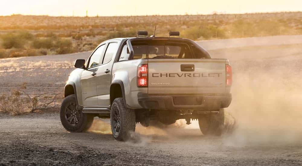 A tan 2021 Chevy Colorado ZR2 is shown from behind in the desert kicking up dust.