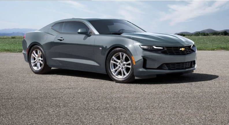 A grey 2021 Chevy Camaro 1LS is shown from the front, angled right, parked in an empty asphalt lot.