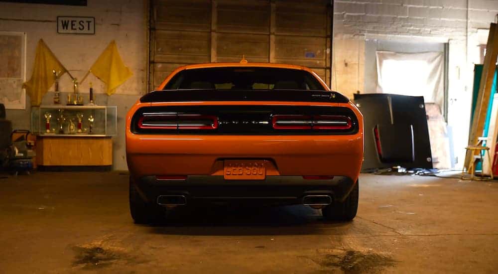 An orange 2021 Dodge Challenger is shown from the rear parked in a garage.