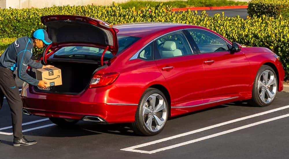 A red 2021 Honda Accord is shown from behind with a package being placed in the trunk.