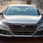 A silver 2021 Honda Accord is shown from the front driving through the city after winning the 2021 Honda Accord vs 2021 Kia K5 comparison.