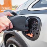 A closeup shows a charger being plugged into a silver 2020 Chevy Bolt EV.