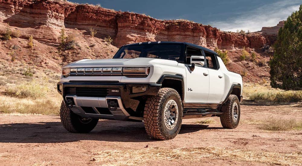 A white 2022 GMC Hummer EV is parked in front of a rock formation.
