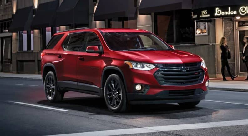 A red 2021 Chevy Traverse RS is parked at a crosswalk in the city after leaving a Hampton Chevy dealership.