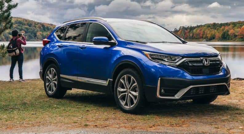 A photographer is behind a blue 2021 Honda CR-V taking pictures of a lake.
