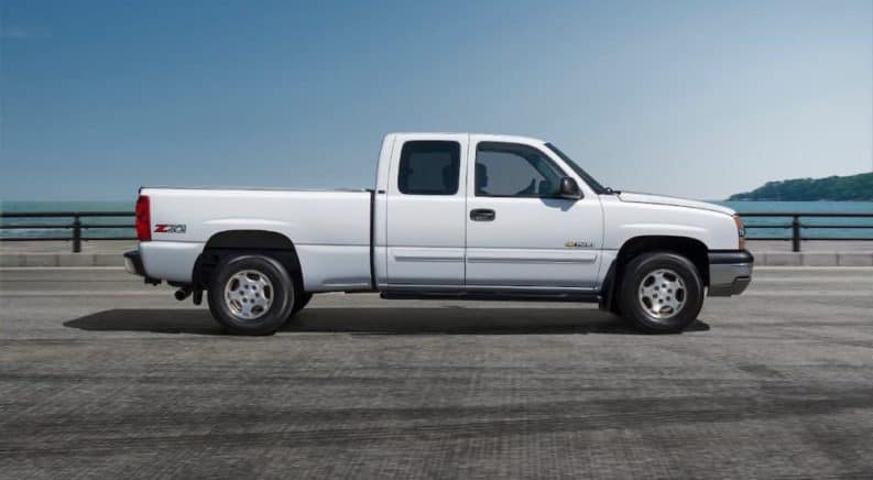 A white 2000 Chevy Silverado is shown from the side in front of a body of water.
