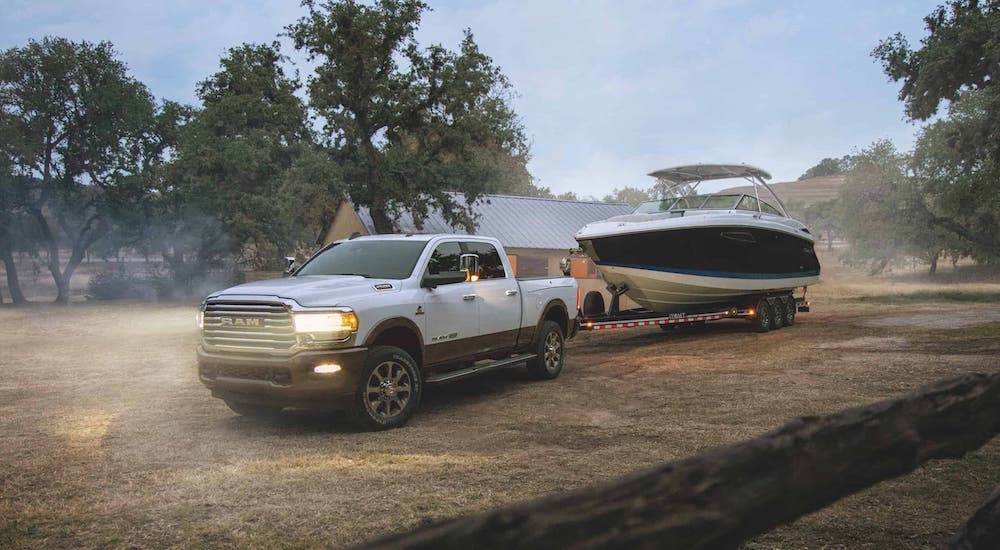 A white 2020 used Ram 2500 is towing a boat on a ranch.