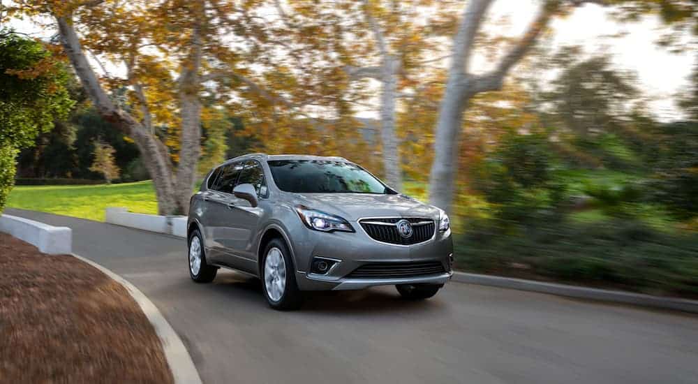 A gray 2021 Buick Envision is shown rounding a corner past blurred trees.