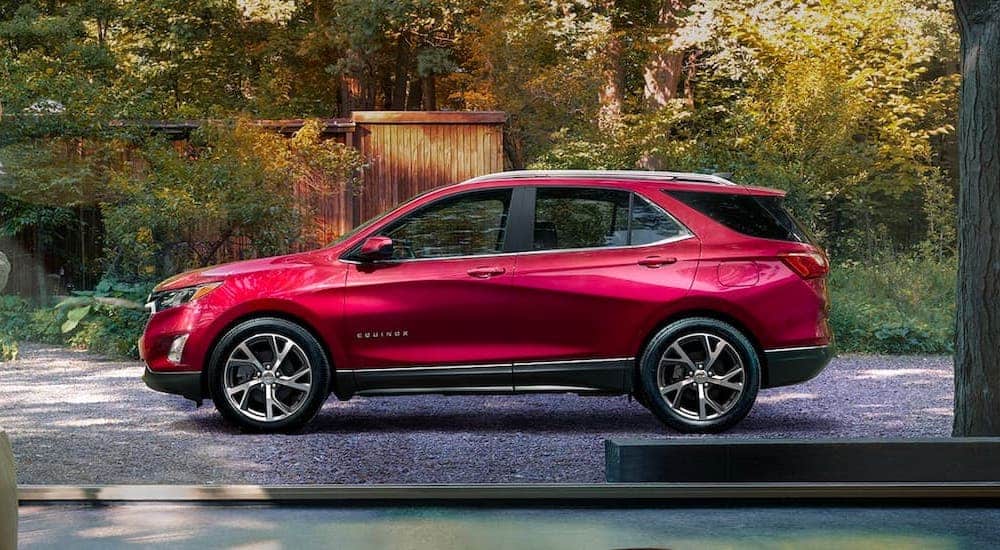 A red 2021 Chevy Equinox is shown from the side parked in front of a wooden shed.