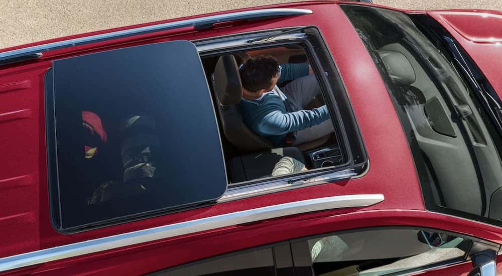 A man is shown in a red 2021 Chevy Equinox from above through the open sun roof.