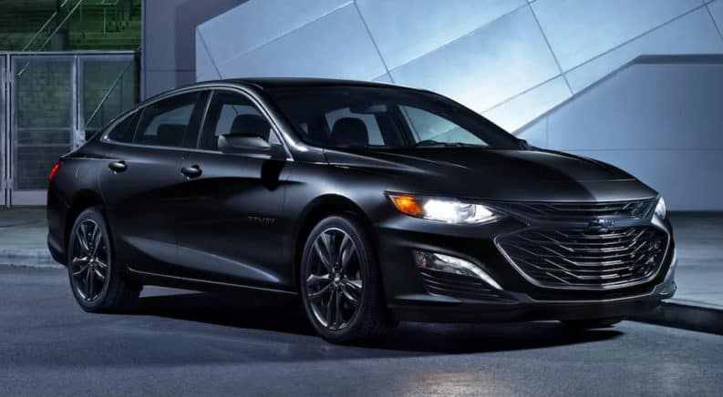 A black 2021 Chevy Malibu is parked in front of a building at night.