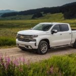 A white 2021 Chevy Silverado High Country is driving through a meadow after winning the 2021 Chevy Silverado 1500 vs 2021 Ford F-150 comparison.