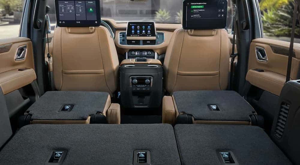 The rear seats are folded down in the tan interior of a 2021 Chevy Tahoe.