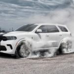 A white 2021 Dodge Durango is doing a burnout in an empty lot.