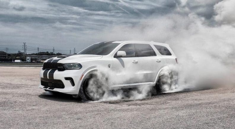 A white 2021 Dodge Durango is doing a burnout in an empty lot.