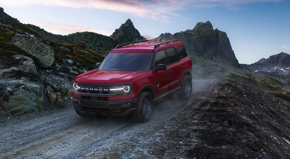 A red 2021 Ford Bronco Sport is driving on a gravel trail on a mountain.
