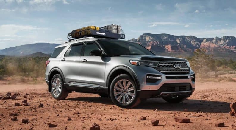 A silver 2021 Ford Explorer is parked in a desert in front of distant mountains.
