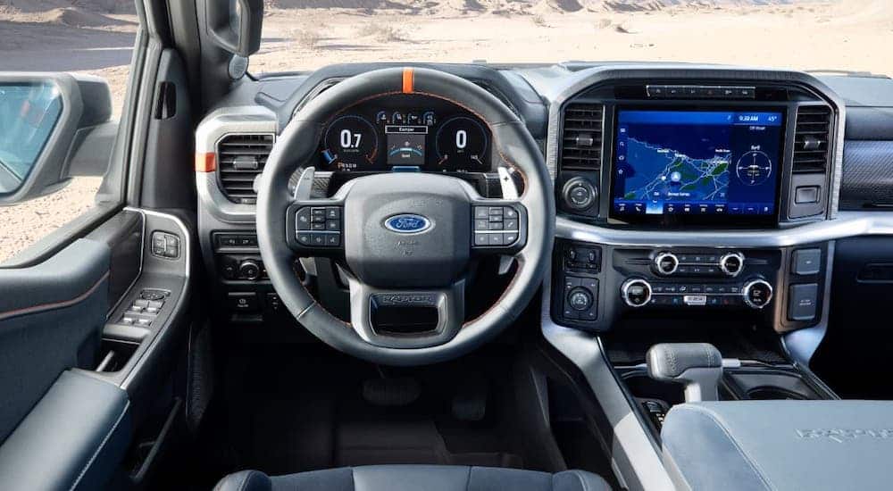 The steering wheel and gray interior of a 2021 Ford F-150 Raptor are shown.