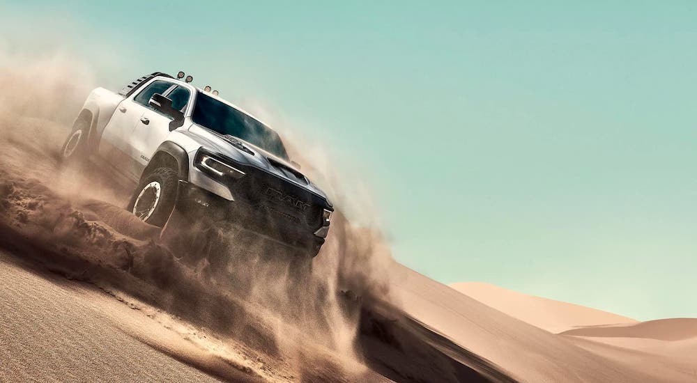 A silver 2021 Ram TRX is kicking up sand as part of the 2021 Ford F-150 Raptor vs 2021 Ram 1500 TRX comparison.