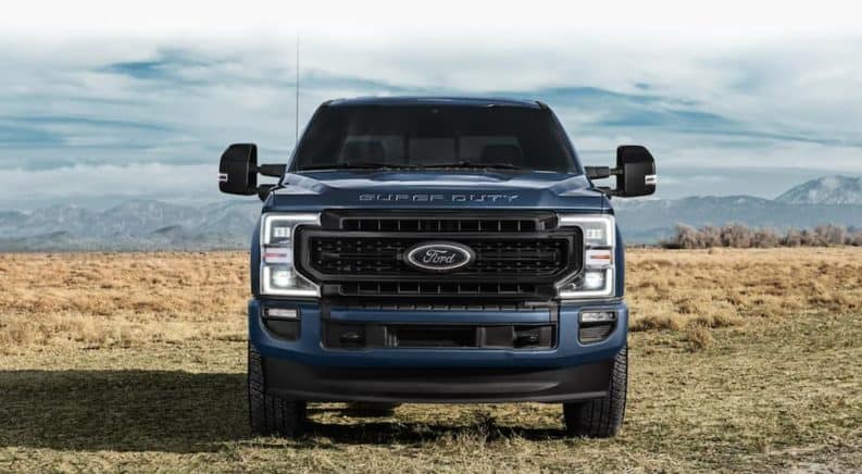 A blue 2021 Ford F-250 Super Duty is shown from the front in a field.