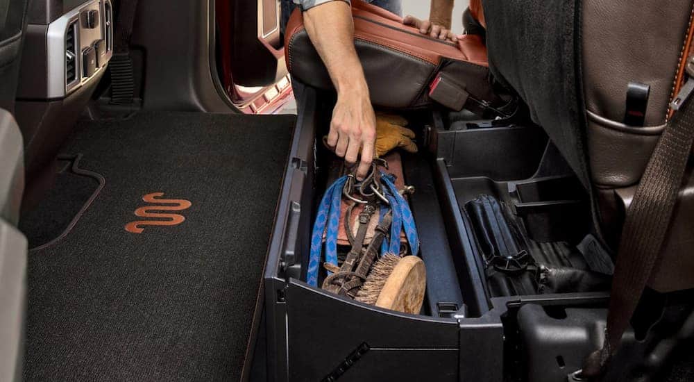 A man is getting tools out of the under seat storage in the back of a 2021 Ford F-250 Super Duty.