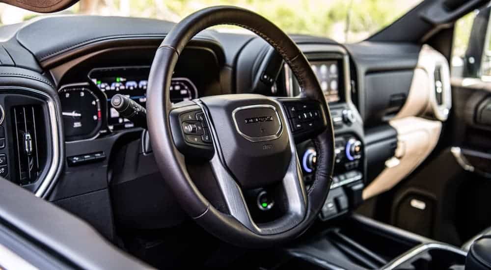 The black leather steering wheel and dashboard are shown in a 2021 GMC Sierra 2500 HD.