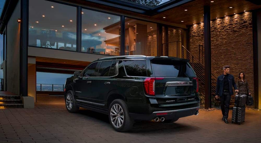 A black 2021 GMC Yukon Denali is parked in the driveway of a modern house. 