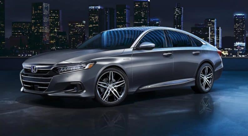 A gray 2021 Honda Accord is shown from the side reflecting blue city lights.