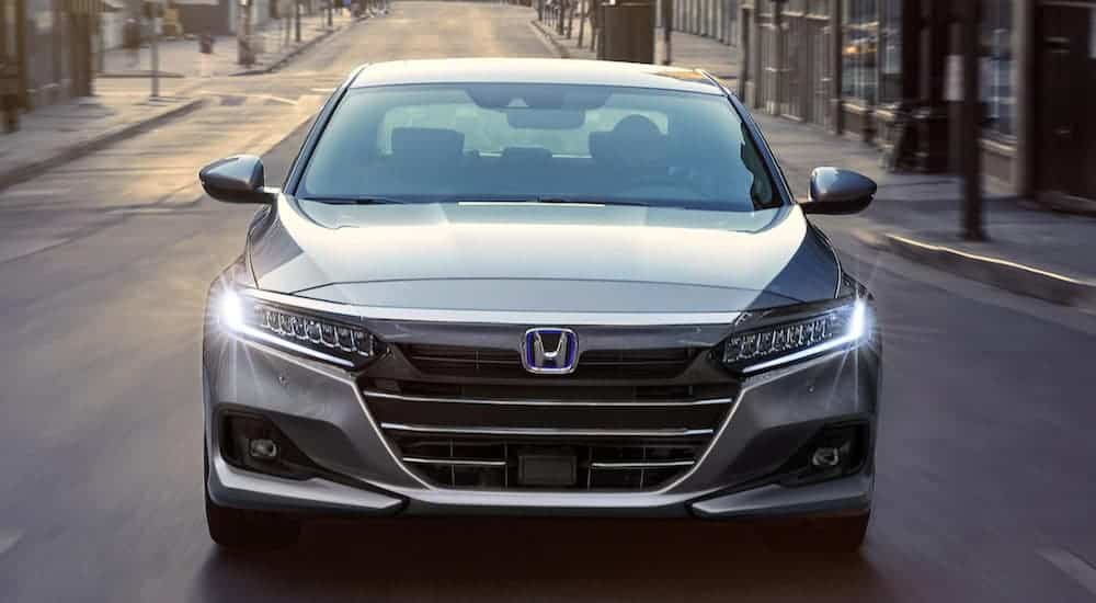 A gray 2021 Honda Accord is shown from the front driving through a city.