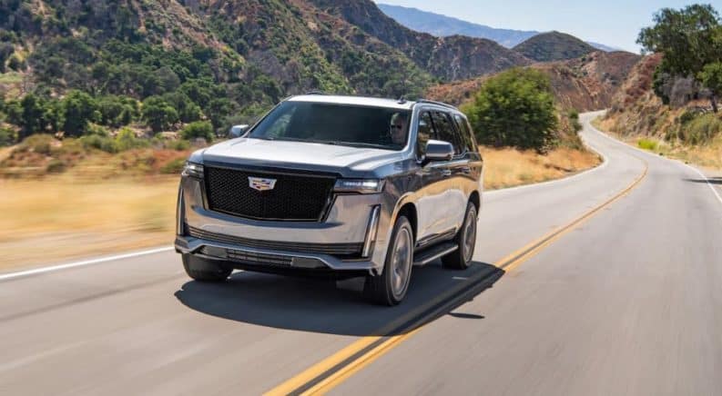 A gray 2021 Cadillac Escalade is driving on a highway.