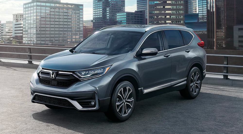 A dark gray 2021 Honda CR-V is parked in front of a city.