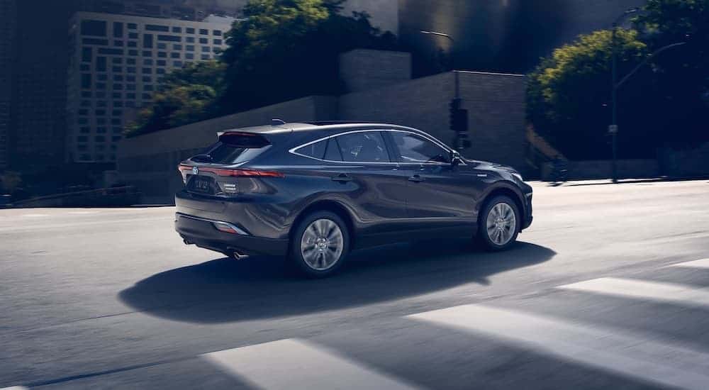 A dark grey 2021 Toyota Venza is shown from the side driving through the city.