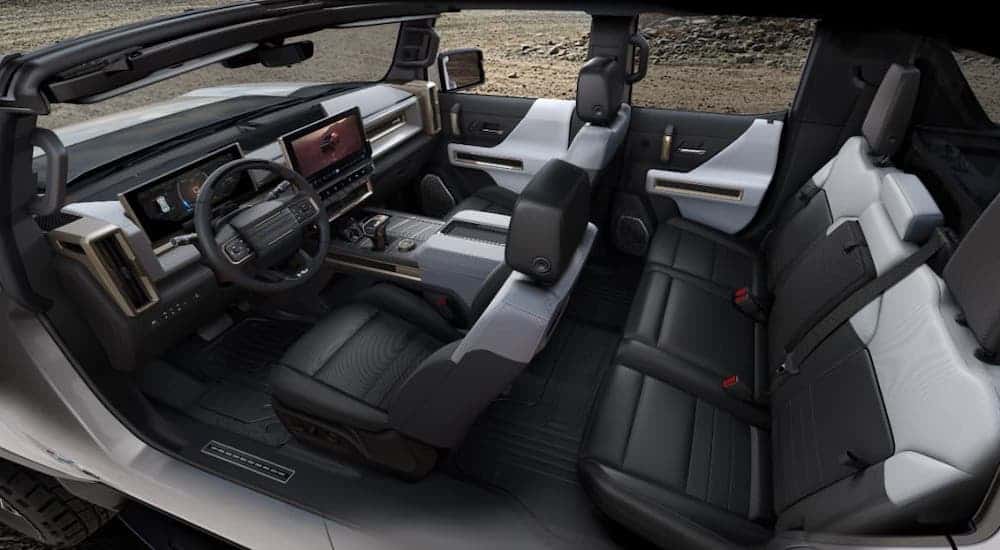 The two rows of seats and black interior of a 2022 GMC Hummer EV Truck are shown from the side.