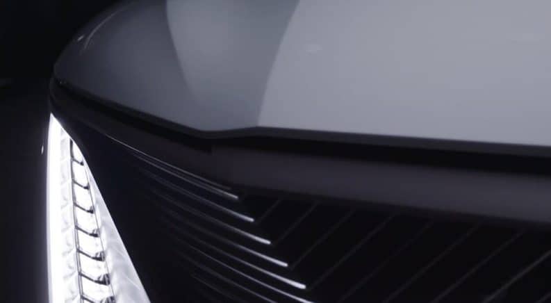 A closeup shows the headlight and hood of a gray Cadillac Celestiq.