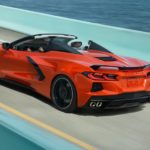 An orange 2021 Chevy Corvette is shown driving down a teal bridge after leaving a Chevy Dealership in NJ.