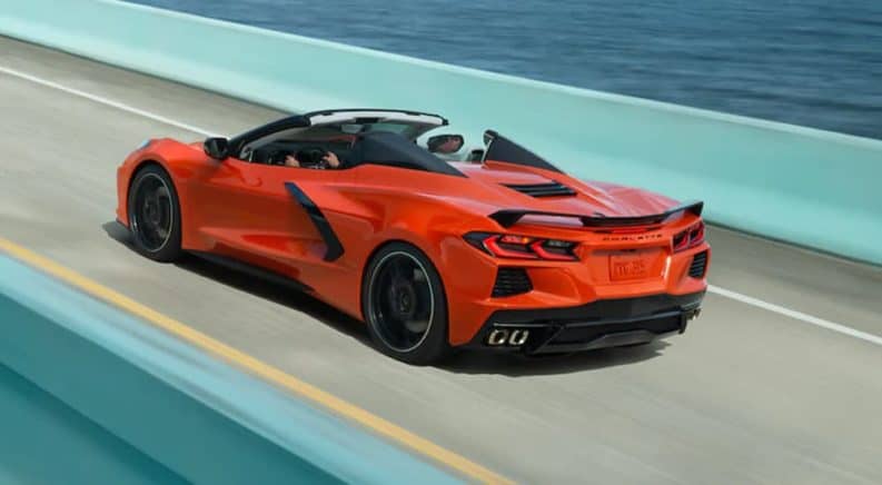 An orange 2021 Chevy Corvette is shown driving down a teal bridge after leaving a Chevy Dealership in NJ.