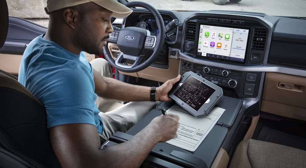 A man is using the center console to work on house plans in a 2021 Ford F-150.