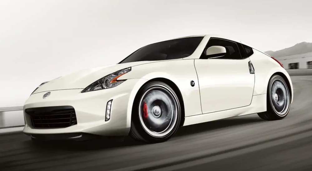 A white 2021 Nissan 370Z is speeding around the corner at a race track.