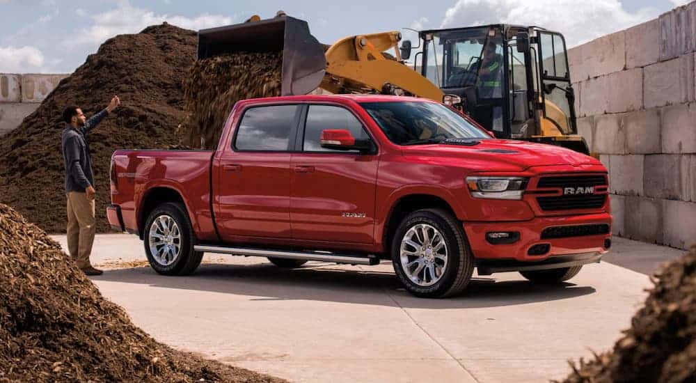 A man is having dirt loaded into a red 2021 Ram 1500.