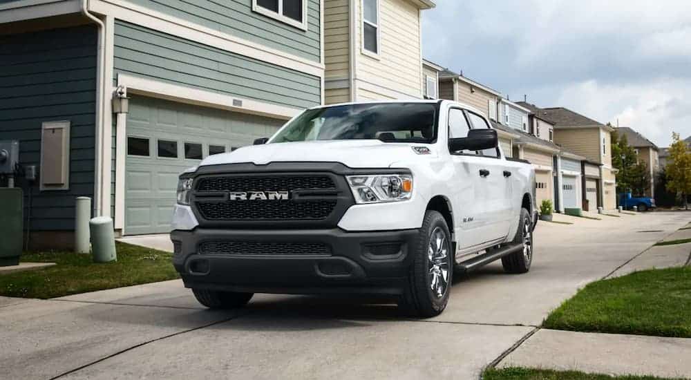 A white 2021 Ram 1500 is parked on a side street in front of houses.