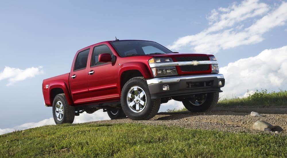 A red 2011 Chevy Colorado is parked on a dirt trail on a hill.