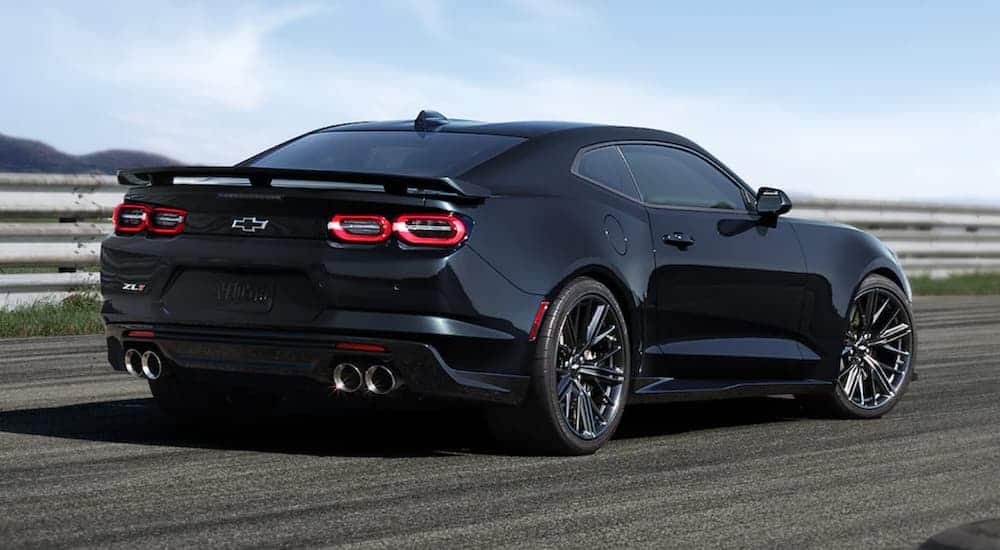 A black 2021 Chevy Camaro is shown from the rear on a racetrack.