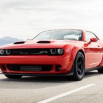 A red 2021 Dodge Challenger is on a highway with distant mountains.