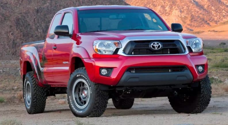 A red 2015 used Toyota Tacoma for sale is parked on dirt.