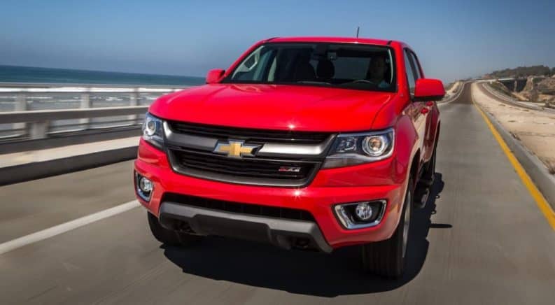 A red 2015 Chevy Colorado Z71 is driving on a coastal highway after leaving a used truck dealer..