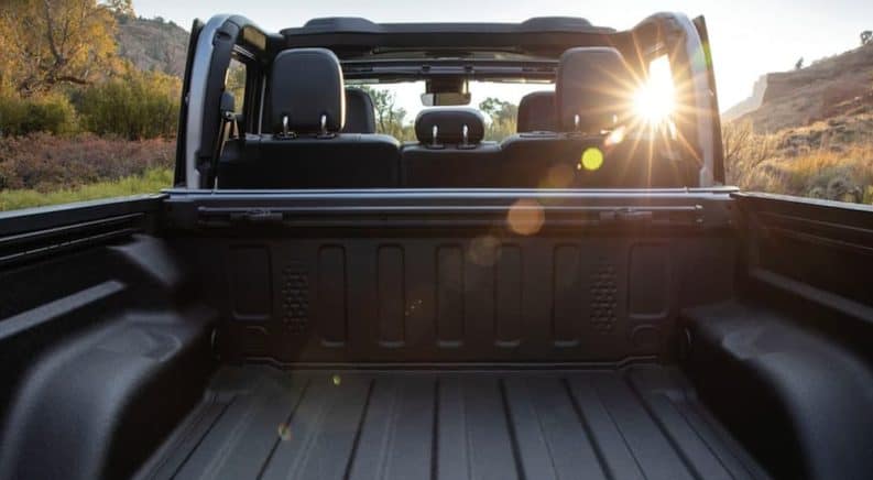 The sun is shining through the seats in a 2020 used Jeep Gladiator Sport with no top, shown from the bed.