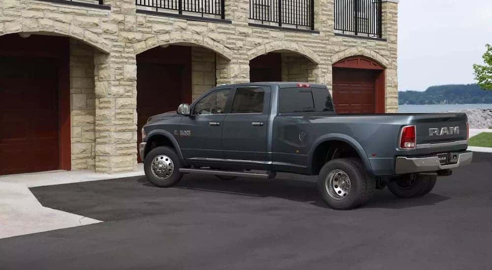 A gray 2017 Ram 3500 is parked in front of a white stone building with several garage doors.