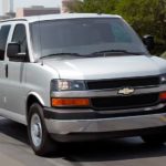 A gray 2021 Chevy Express Van is driving down an empty highway.