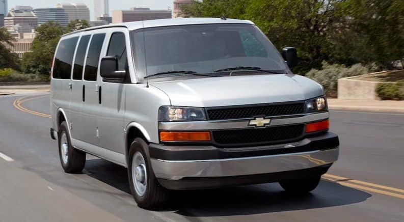 A gray 2021 Chevy Express Van is driving down an empty highway.